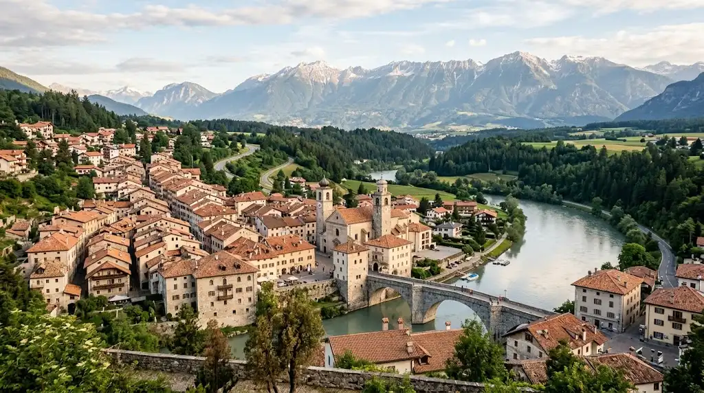 Historic European town with terracotta rooftops and alpine mountains in the distance.